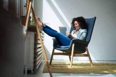 Smiling businesswoman working on laptop at workplace - JOSEF13016