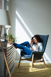 Glückliche Geschäftsfrau mit Mobiltelefon auf einem Stuhl sitzend - JOSEF13027