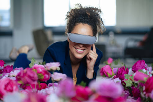 Lächelnde Geschäftsfrau mit VR-Brille bei Blumen im Büro - JOSEF13047