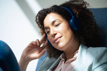 Businesswoman listening music and relaxing in office - JOSEF13048