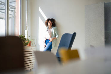 Selbstbewusste Geschäftsfrau, die sich im Büro an die Wand lehnt - JOSEF13054