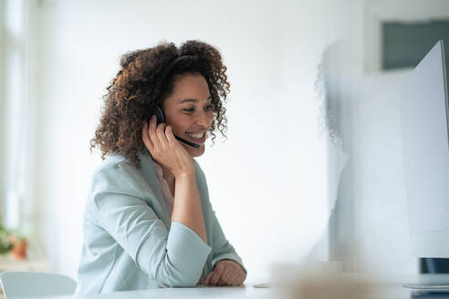 Glückliche Geschäftsfrau mit Headset am Arbeitsplatz - JOSEF13063