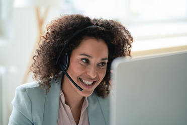 Smiling customer service representative wearing headset at workplace - JOSEF13067
