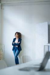 Thoughtful businesswoman with arms crossed leaning on wall - JOSEF13072