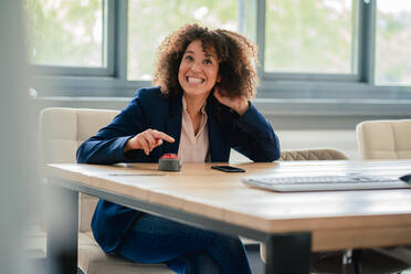 Cheerful businesswoman with buzzer button in board room - JOSEF13089