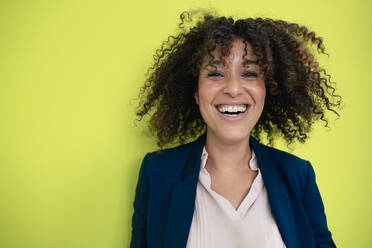 Businesswoman with curly hair laughing in front of wall - JOSEF13101