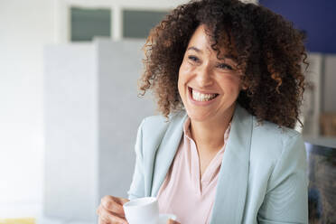 Happy businesswoman having coffee cup in break time at office - JOSEF13157