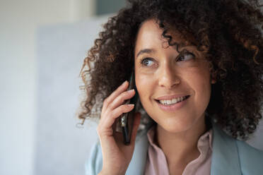 Contemplative businesswoman talking on smart phone at office - JOSEF13160