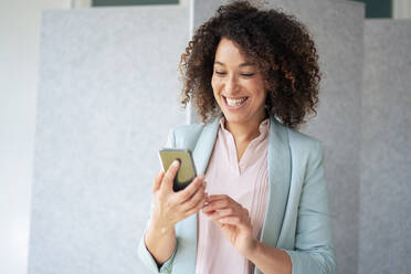 Fröhliche Geschäftsfrau mit Mobiltelefon im Büro - JOSEF13161