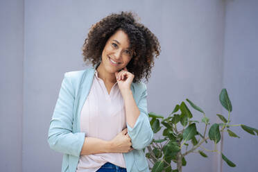 Smiling businesswoman standing in front of wall - JOSEF13169