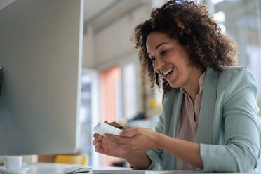 Happy businesswoman doing payment through credit card in office - JOSEF13190