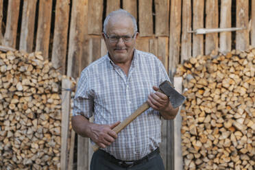 Senior man holding axe standing at back yard - OSF00904