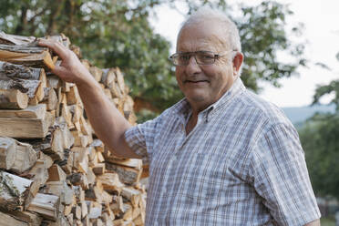 Lächelnder älterer Mann bei einem Stapel Brennholz - OSF00905