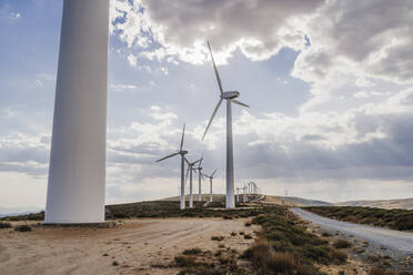 Aufgereihte Windturbinen in einem Bauernhof mit Wolken am Himmel - EBBF06283