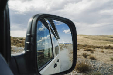 Reflection of wind farm on side mirror of van - EBBF06284