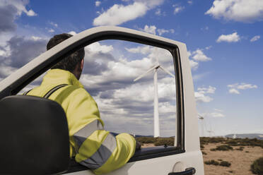 Techniker betrachtet die Turbinen an der Tür eines Lieferwagens in einem Windpark - EBBF06294