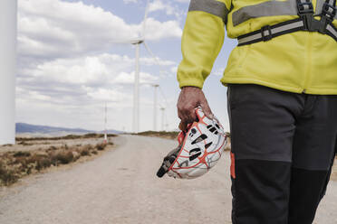 Die Hand eines Technikers hält einen Helm im Windpark - EBBF06300