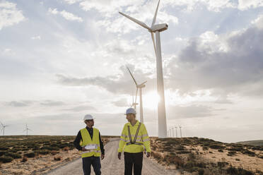 Ältere Techniker diskutieren an einem sonnigen Tag im Windpark - EBBF06340