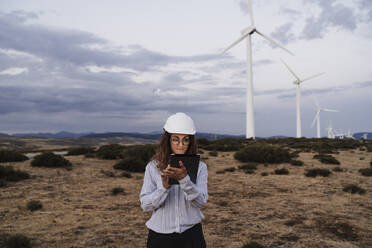 Engineer working on tablet PC at wind farm - EBBF06382