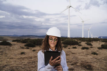 Smiling engineer using tablet PC at wind farm - EBBF06383