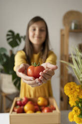 Mädchen hält zu Hause eine frische Tomate in der Hand - LESF00131