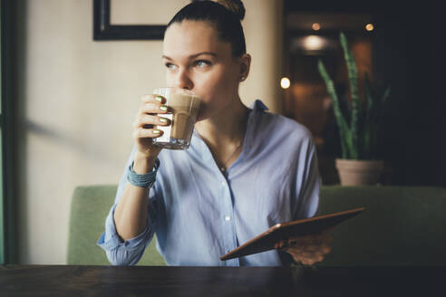 Frau mit Tablet-PC trinkt Kaffee im Restaurant - OYF00724