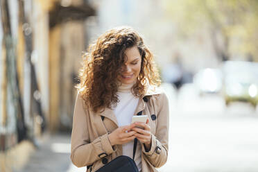 Happy woman using mobile phone on sunny day - OYF00728