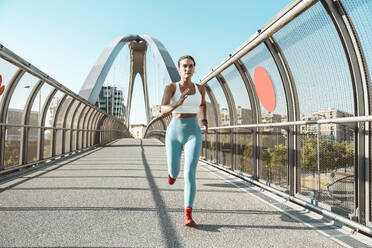 Young woman running on footbridge - OIPF02382