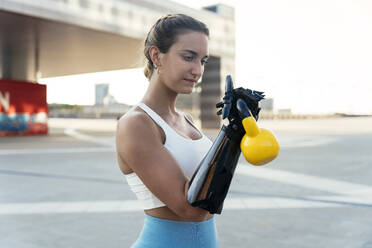 Junge Frau mit Armprothese beim Training mit der Kettlebell - OIPF02398