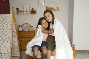 Sisters wrapped in blanket embracing each other - LESF00146