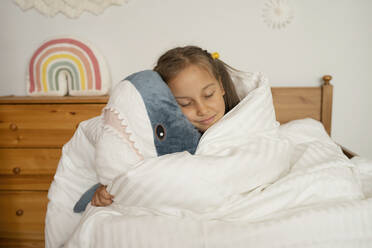 Mädchen schläft mit einem Spielzeug-Hai unter einer weißen Decke im Kinderzimmer - LESF00151