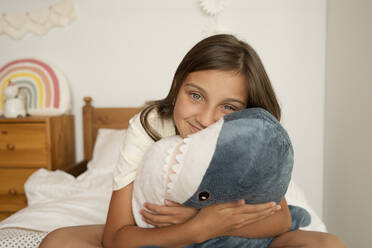 Mädchen umarmt ihren Spielzeug-Hai im Kinderzimmer zu Hause - LESF00160