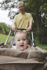 Niedliches kleines Mädchen im Kinderwagen mit Vater im Hintergrund - IHF01199