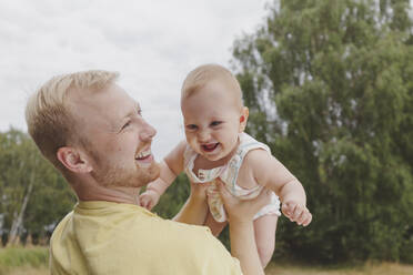 Happy father playing with daughter in park - IHF01211