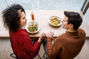 Fröhliches multiethnisches Paar beim gesunden Frühstück im Restaurant - ADSF37842