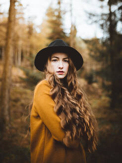 Porträt einer schönen jungen Frau, die einen Hut trägt und auf dem Lande steht - ADSF37952