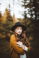 Porträt einer schönen jungen Frau, die einen Hut trägt und auf dem Lande steht - ADSF37956