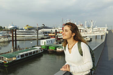 Happy woman standing by railing on sunny day at Port of Hamburg, Germany - IHF01230