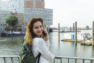 Happy woman talking on smart phone at Port of Hamburg, Germany - IHF01233