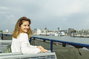 Smiling woman sitting in ferry boat on sunny day - IHF01252