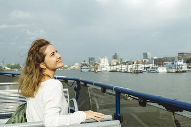 Happy woman sitting in ferry boat on sunny day - IHF01253