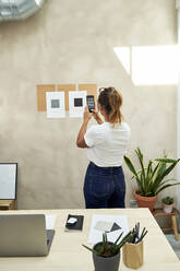 Freelancer taking picture of business strategy on wall at home office - VEGF05948