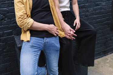 Gay couple holding hands in front of wall - ASGF02882