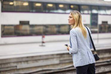 Businesswoman with blond hair waiting for train at station - WPEF06365