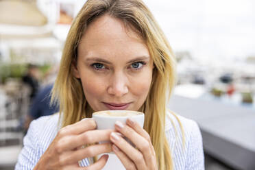 Smiling blond businesswoman holding coffee cup - WPEF06376