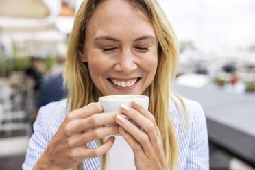 Happy businesswoman with eyes closed holding coffee cup - WPEF06377