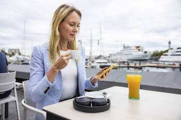 Geschäftsfrau mit Smartphone und Kaffeetasse in einem Café - WPEF06378