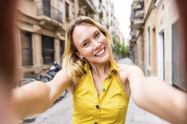 Fröhliche Frau nimmt Selfie in Gasse - WPEF06386