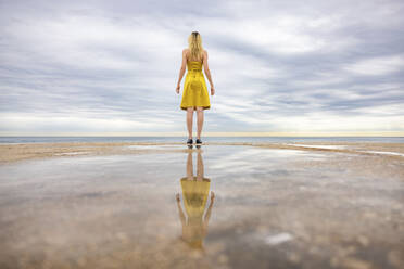 Frau steht an der Promenade und schaut aufs Meer - WPEF06390