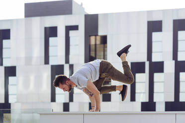 Sportlicher Mann macht Parkour-Gleichgewichtsübungen im Freien in einer städtischen Szene - ADSF38068